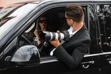 Private detectives with modern camera spying from car