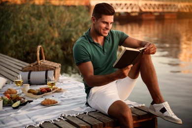 Photo of Man reading book on pier at picnic