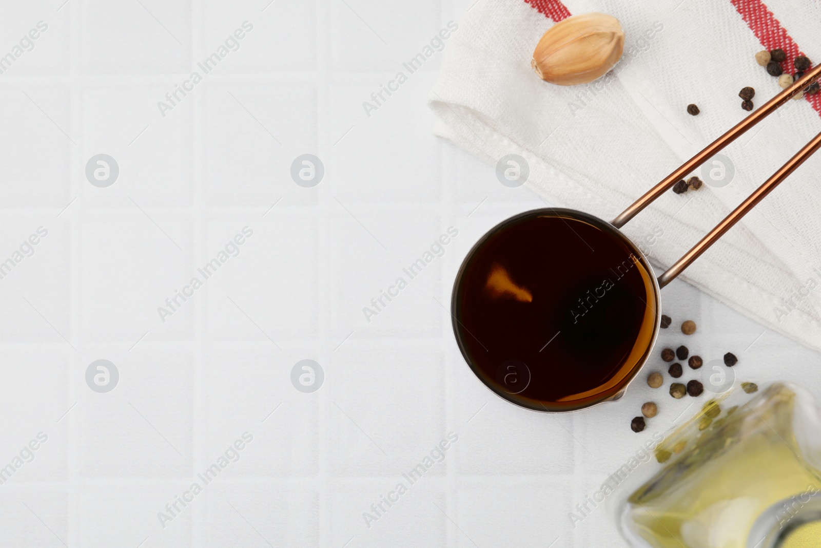 Photo of Metal small saucepan with balsamic vinegar and ingredients on white tiled table, flat lay. Space for text