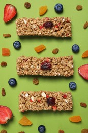 Photo of Tasty granola bars and ingredients on green background, flat lay