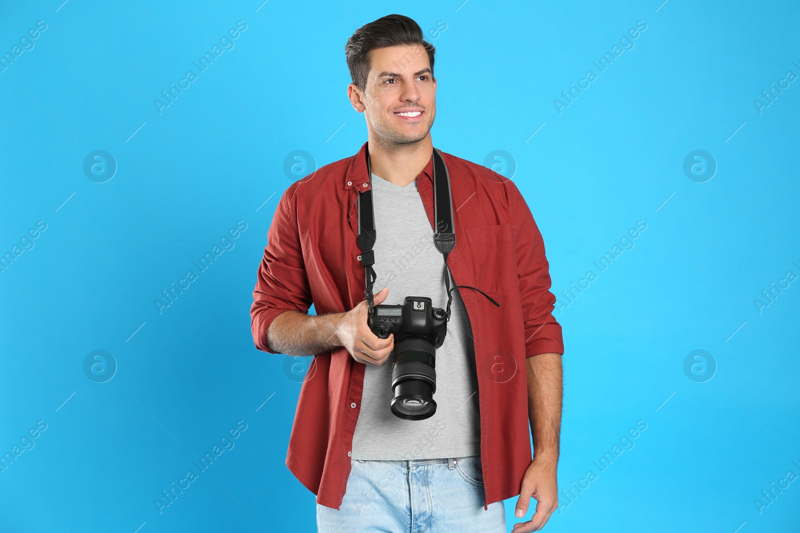 Photo of Professional photographer working on light blue background in studio