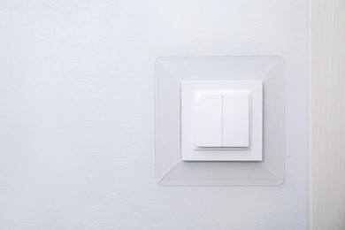 Photo of Modern plastic light switch on white wall, space for text