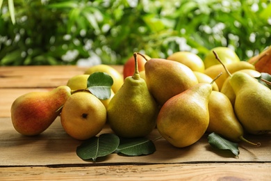 Ripe pears on wooden table against blurred background