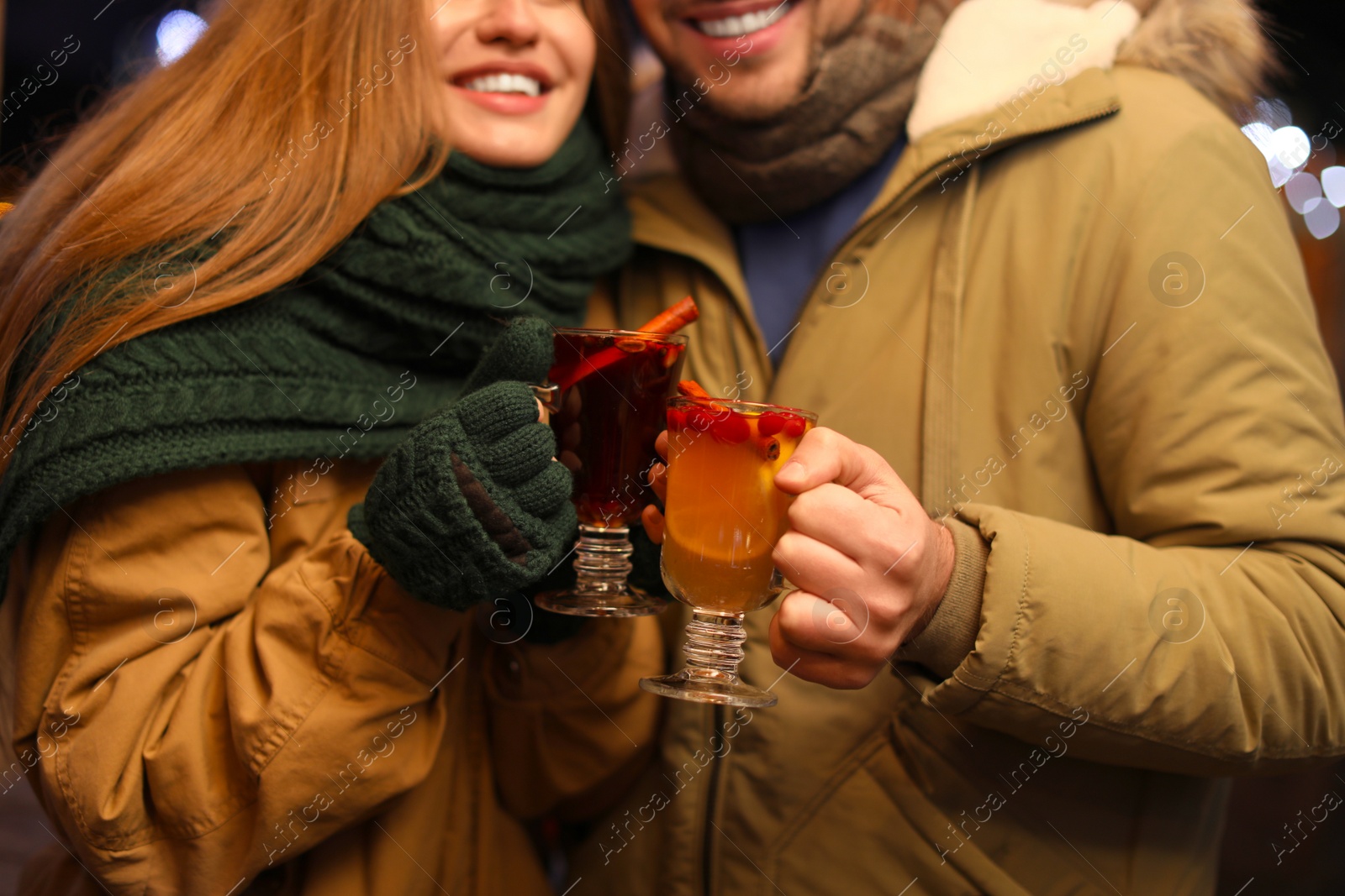 Photo of Happy couple with mulled wine at winter fair, closeup