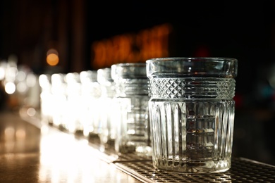 Photo of Row of empty clean glasses on counter in bar. Space for text