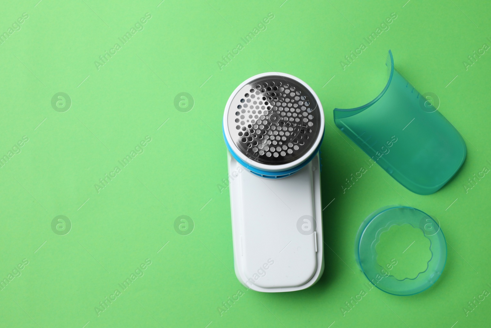 Photo of Modern fabric shaver and parts on green background, flat lay. Space for text