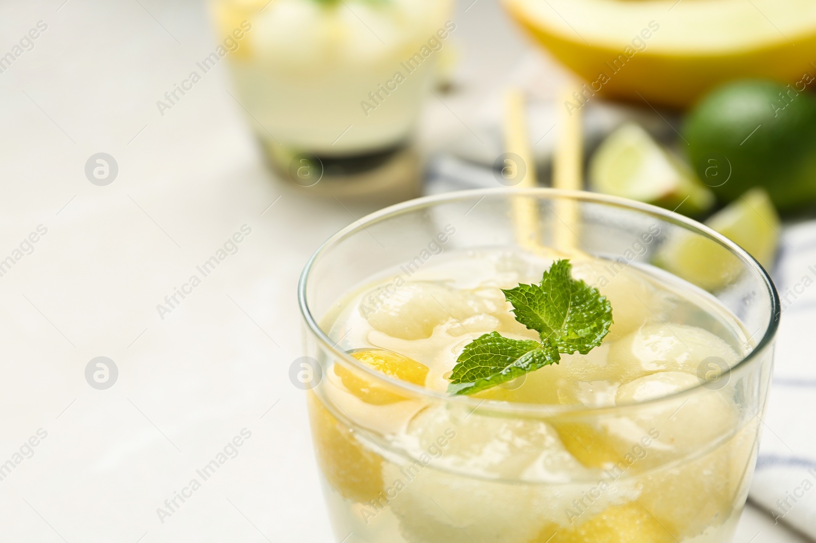 Photo of Glass of melon ball cocktail with mint on table, closeup