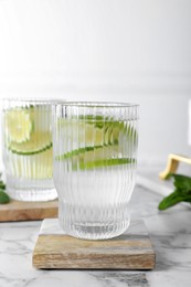 Photo of Glass of lemonade with stylish cup coasters on marble table