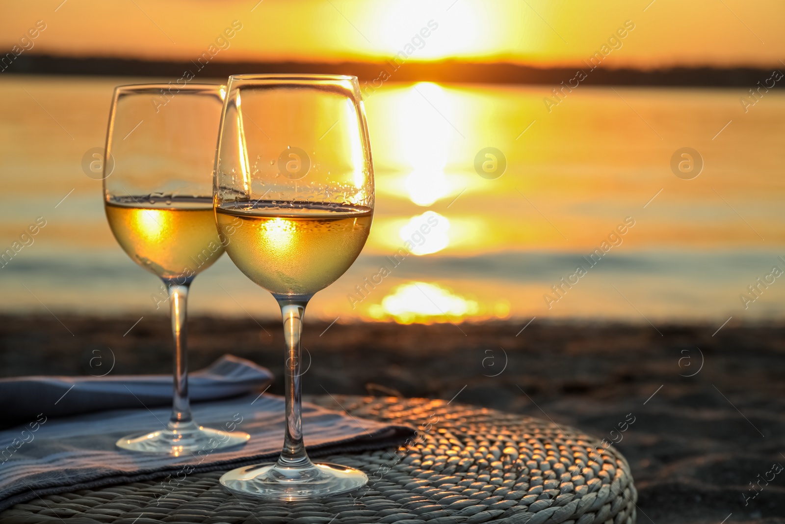 Photo of Glasses of delicious wine on riverside at sunset