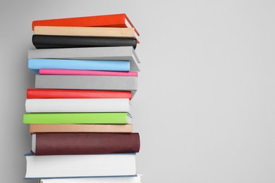 Photo of Stack of different books on light gray background, space for text