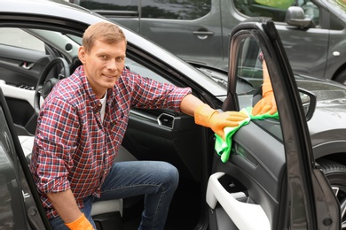 Man washing car door with rag outdoors