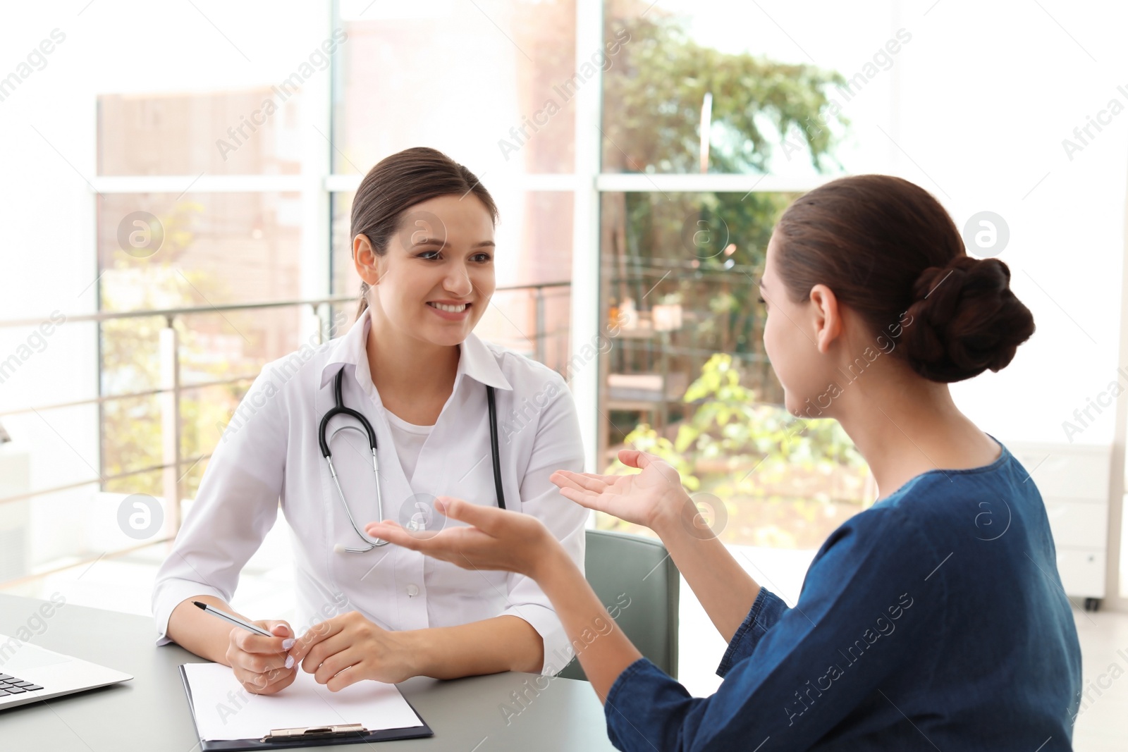 Photo of Young doctor listening to patient's complaints in hospital