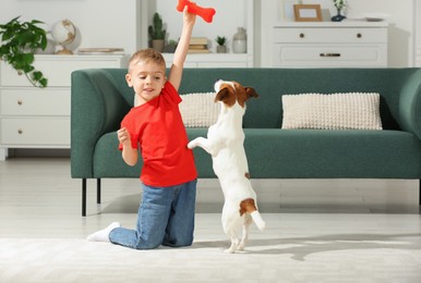Photo of Little boy playing with his cute dog at home, space for text. Adorable pet