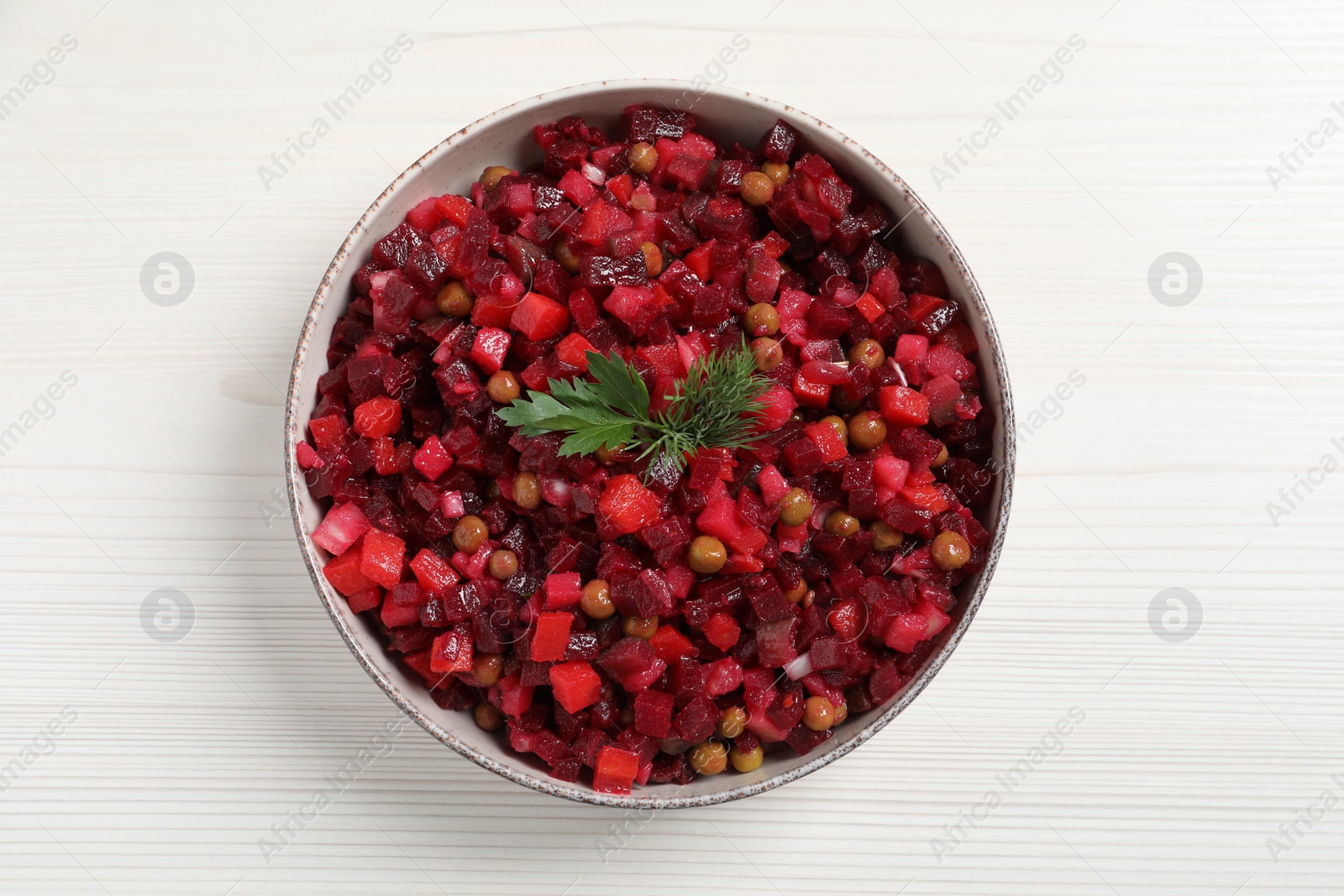 Photo of Bowl of delicious fresh vinaigrette salad on white wooden table, top view