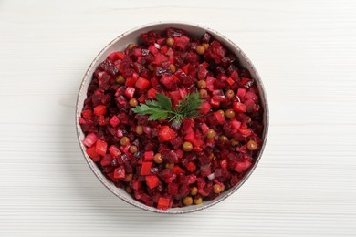 Photo of Bowl of delicious fresh vinaigrette salad on white wooden table, top view