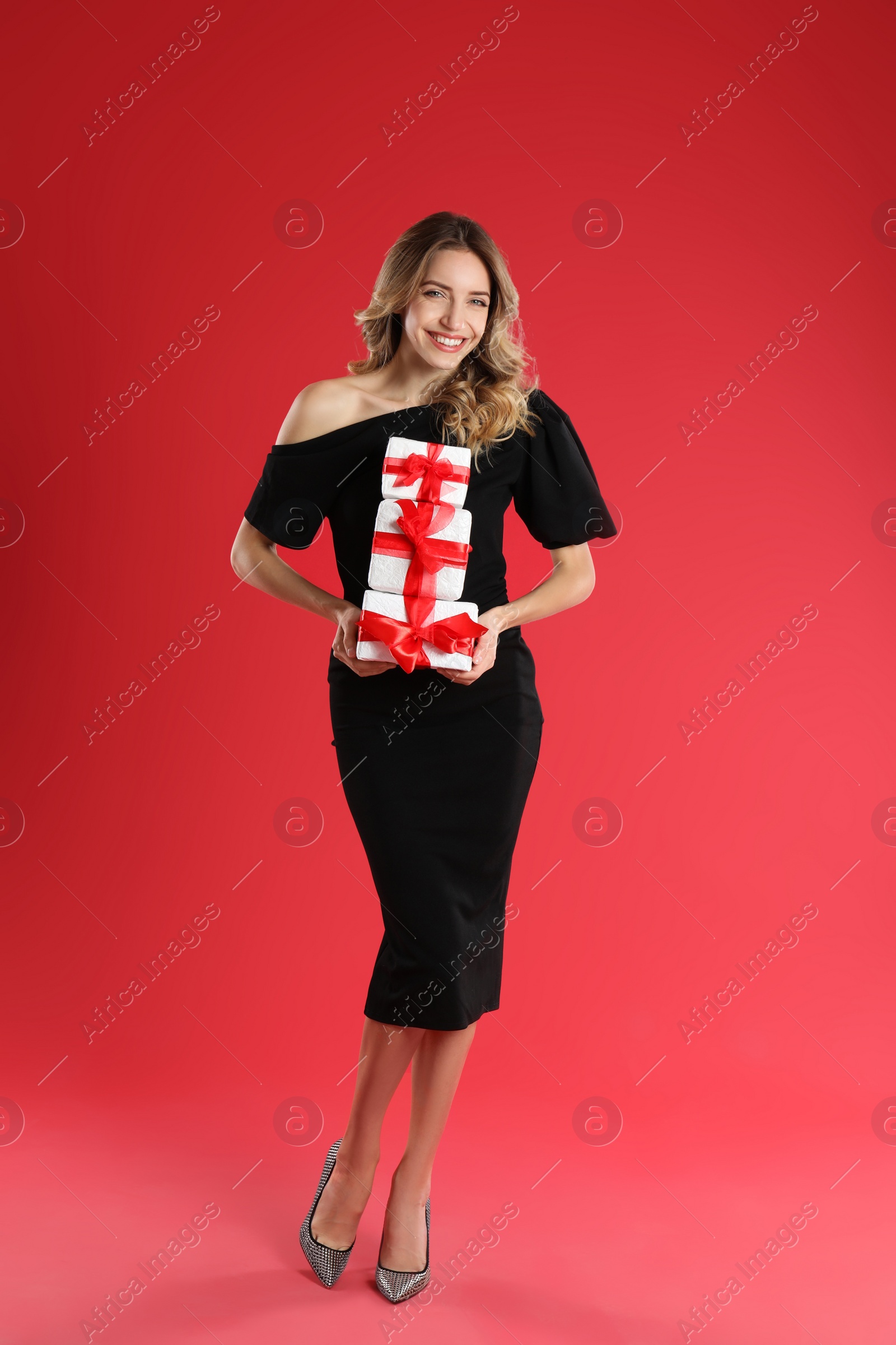 Photo of Beautiful young woman with Christmas presents on red background