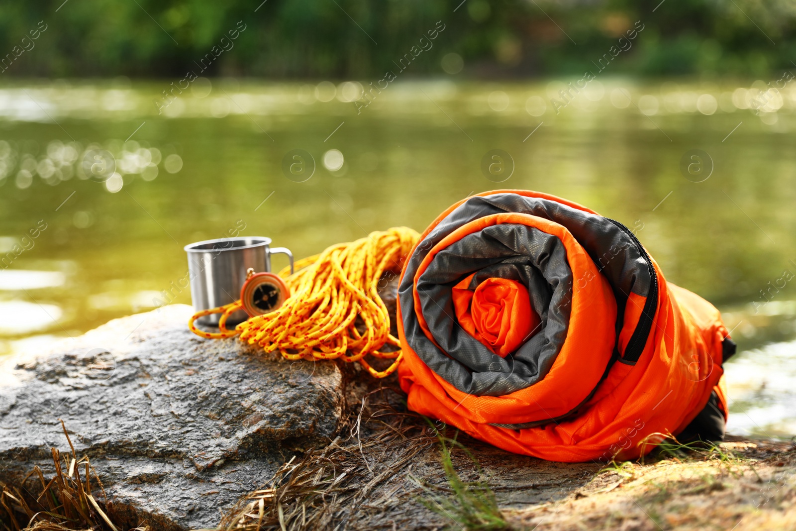 Photo of Rolled sleeping bag and other camping gear near lake