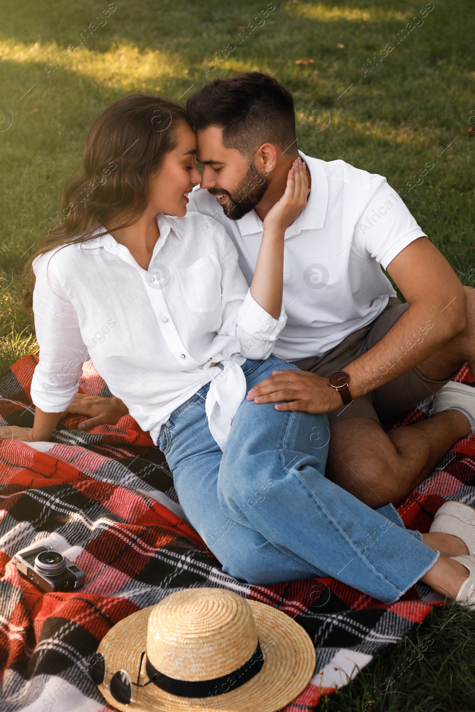 Photo of Lovely couple enjoying time together on picnic plaid in park