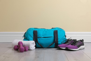 Photo of Bag with different sports equipment on wooden floor indoors