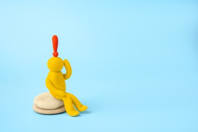 Photo of Human figure madeyellow plasticine with exclamation mark as solution idea on light blue background. Space for text