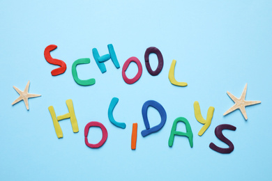 Phrase School Holidays made of modeling clay on light blue background, top view