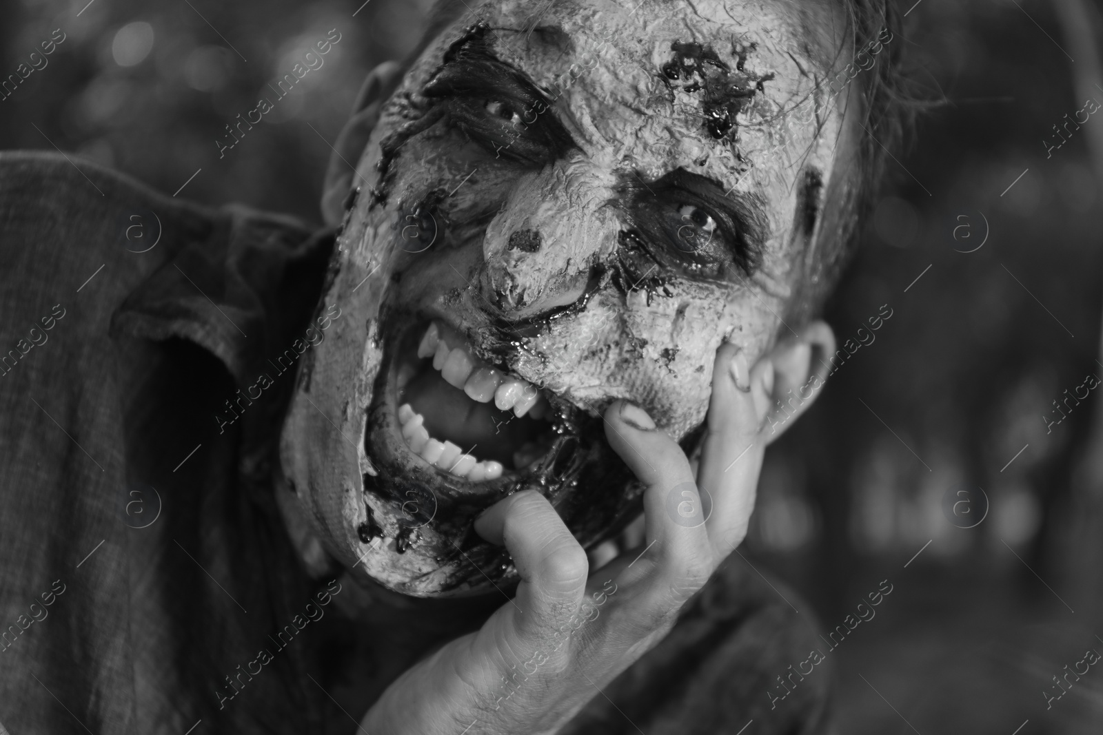 Photo of Scary zombie outdoors, black and white effect. Halloween monster