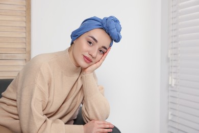 Photo of Cancer patient. Young woman with headscarf near window indoors, space for text