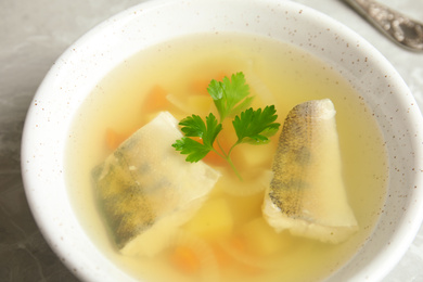 Delicious fish soup in bowl on table, closeup view