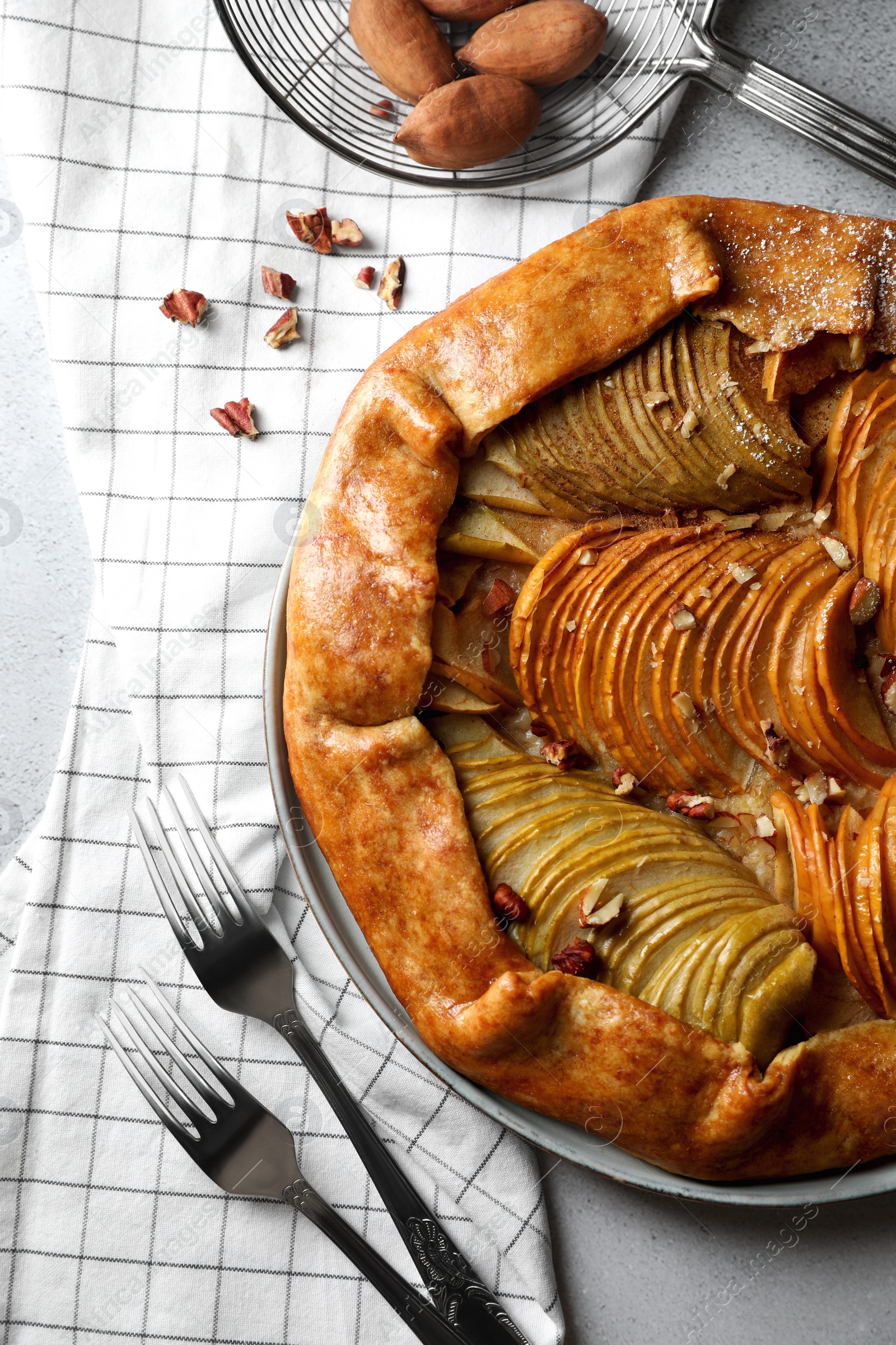 Photo of Delicious apple galette with nuts served on grey textured table, flat lay