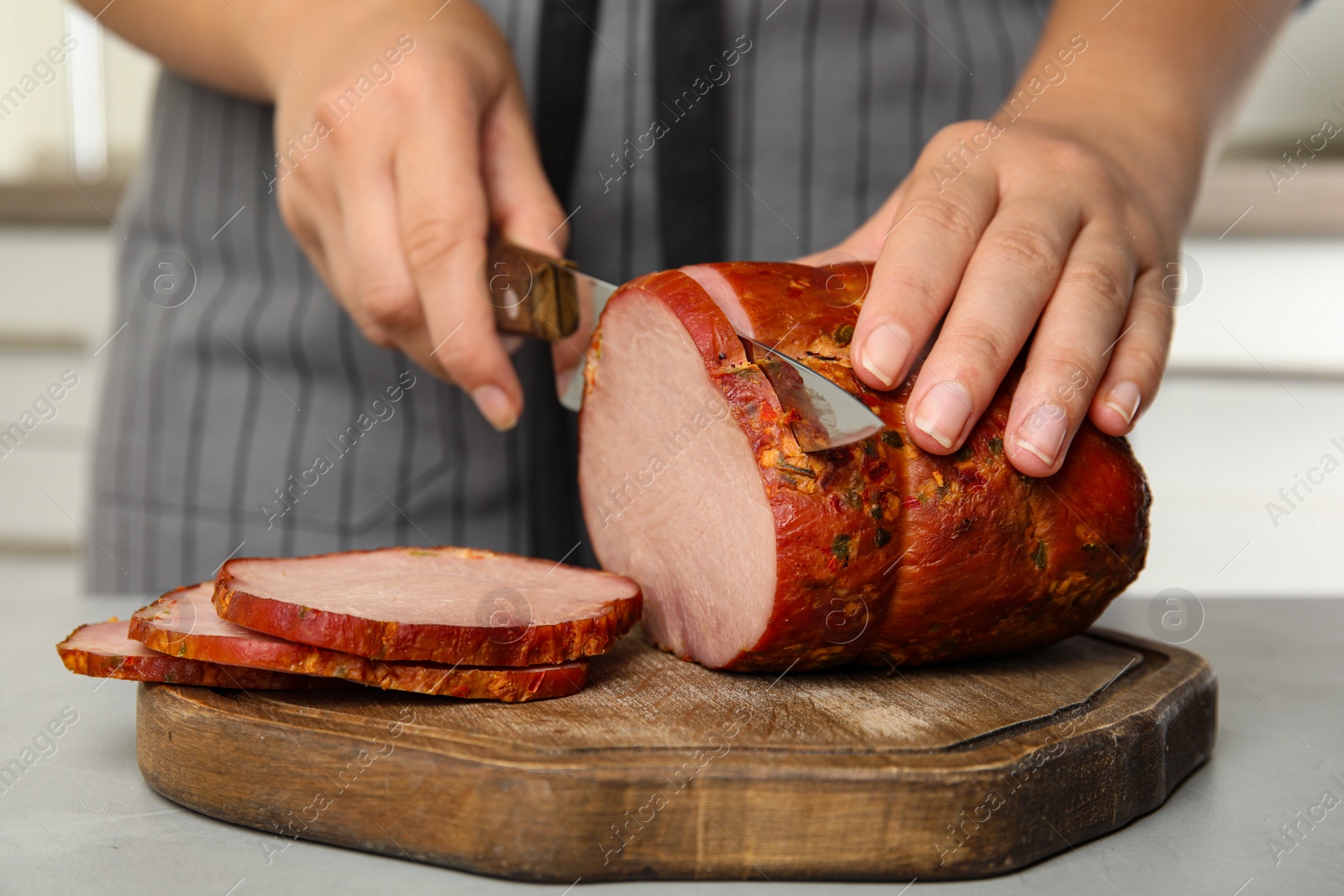 Photo of Woman cutting ham at table in kitchen, closeup