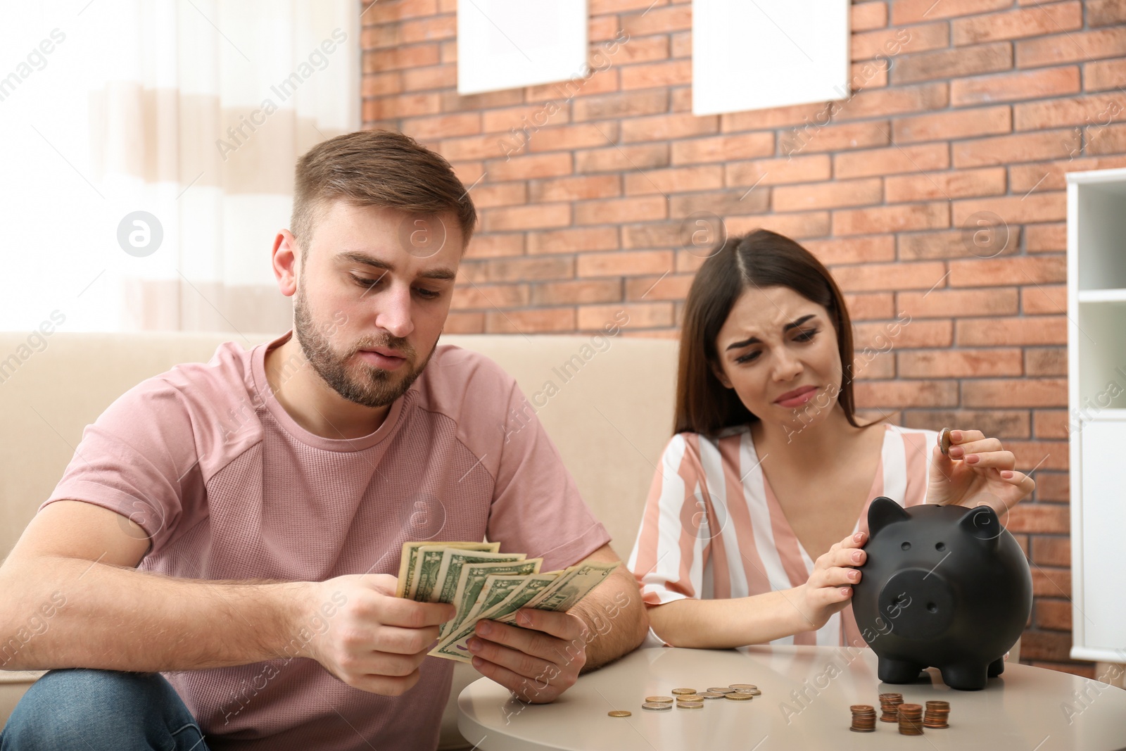 Photo of Unhappy young couple with money at home. Financial problems