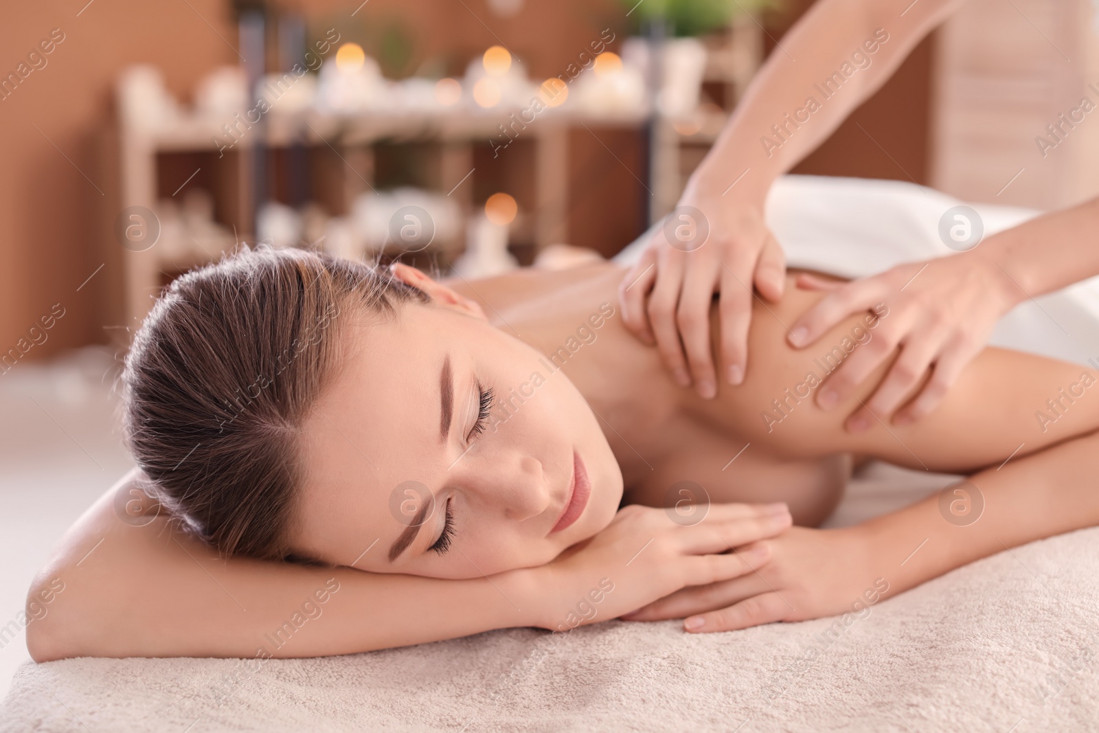 Photo of Young woman enjoying massage in spa salon