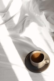 Photo of Cup of aromatic coffee on bed in morning, above view. Space for text