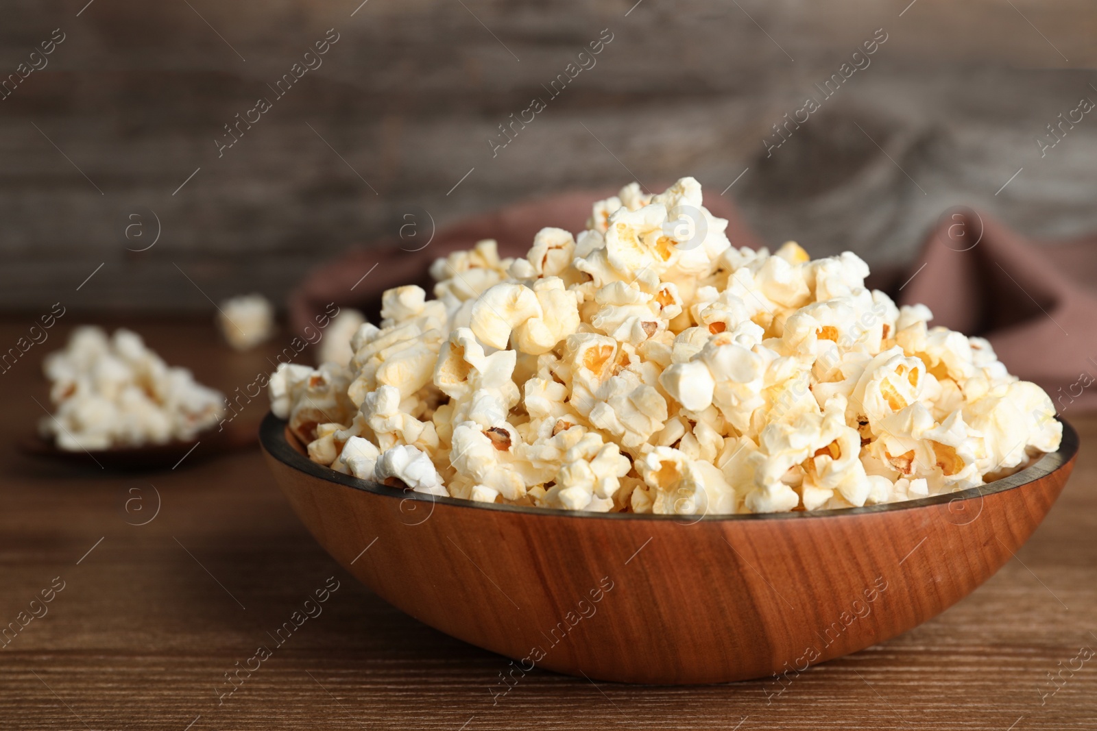 Photo of Wooden bowl with tasty popcorn on table