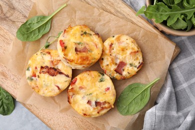 Delicious egg muffins with cheese and bacon on grey table, flat lay