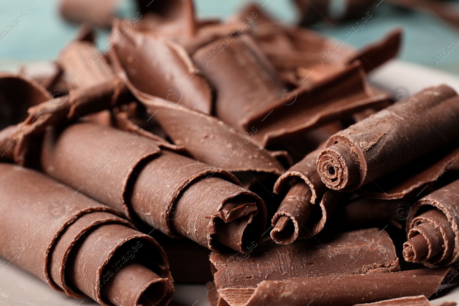 Photo of Tasty chocolate curls for decor on plate, closeup