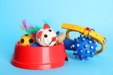 Photo of Various pet toys, collar and bowl on light blue background