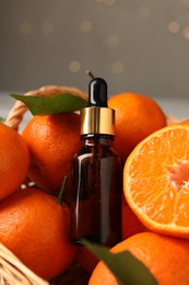 Photo of Bottle of tangerine essential oil and fresh fruits in basket