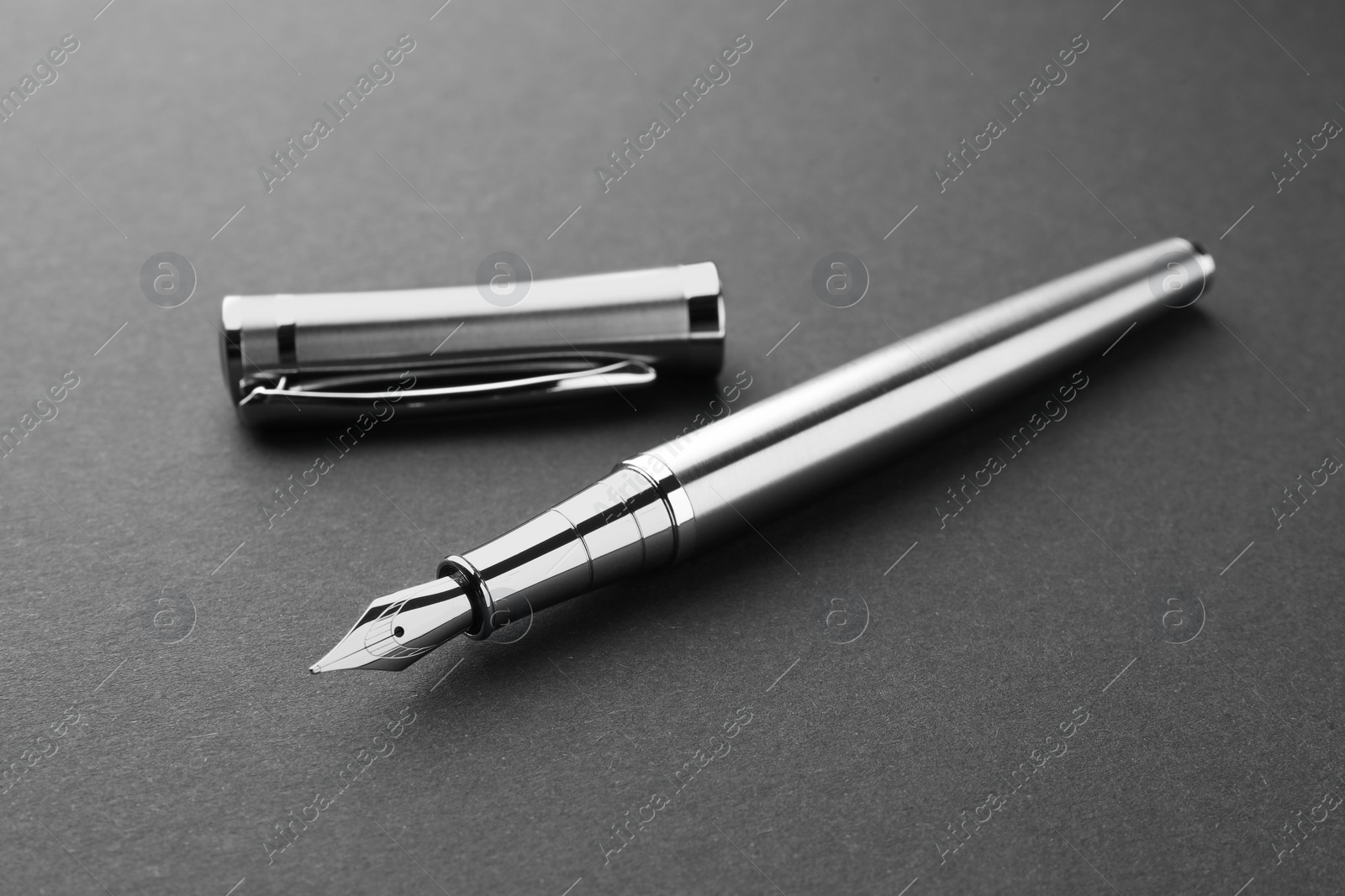Photo of Stylish silver fountain pen with cap on dark background, closeup