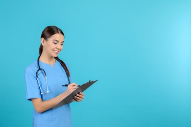 Photo of Portrait of medical assistant with stethoscope and clipboard on color background. Space for text