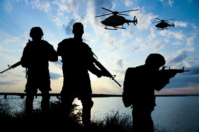 Image of Silhouettes of soldiers in uniform with assault rifles and military helicopters patrolling outdoors