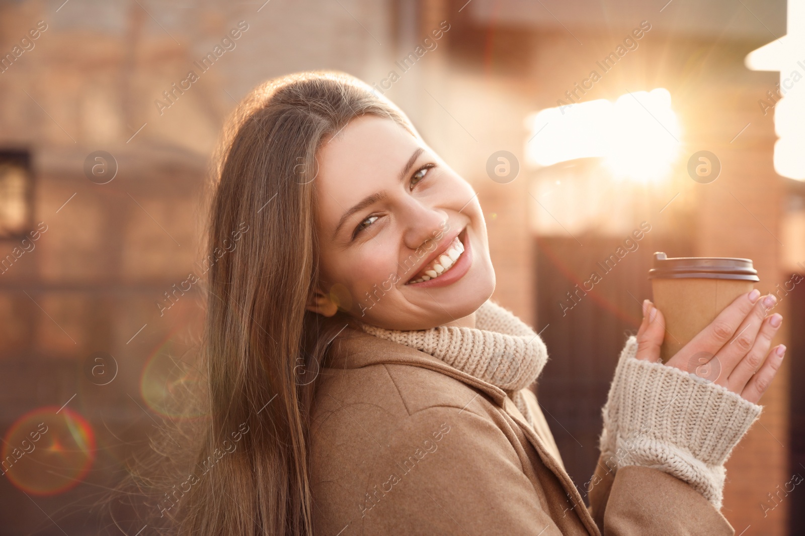 Photo of Young woman with cup of coffee on city street in morning