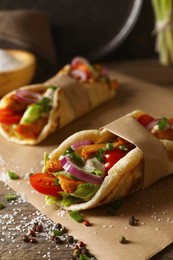Photo of Delicious pita wraps with meat and vegetables on wooden table, closeup