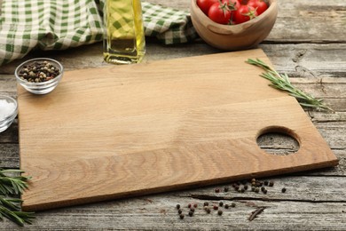 Photo of Cutting board, rosemary, oil and pepper on wooden table. Space for text