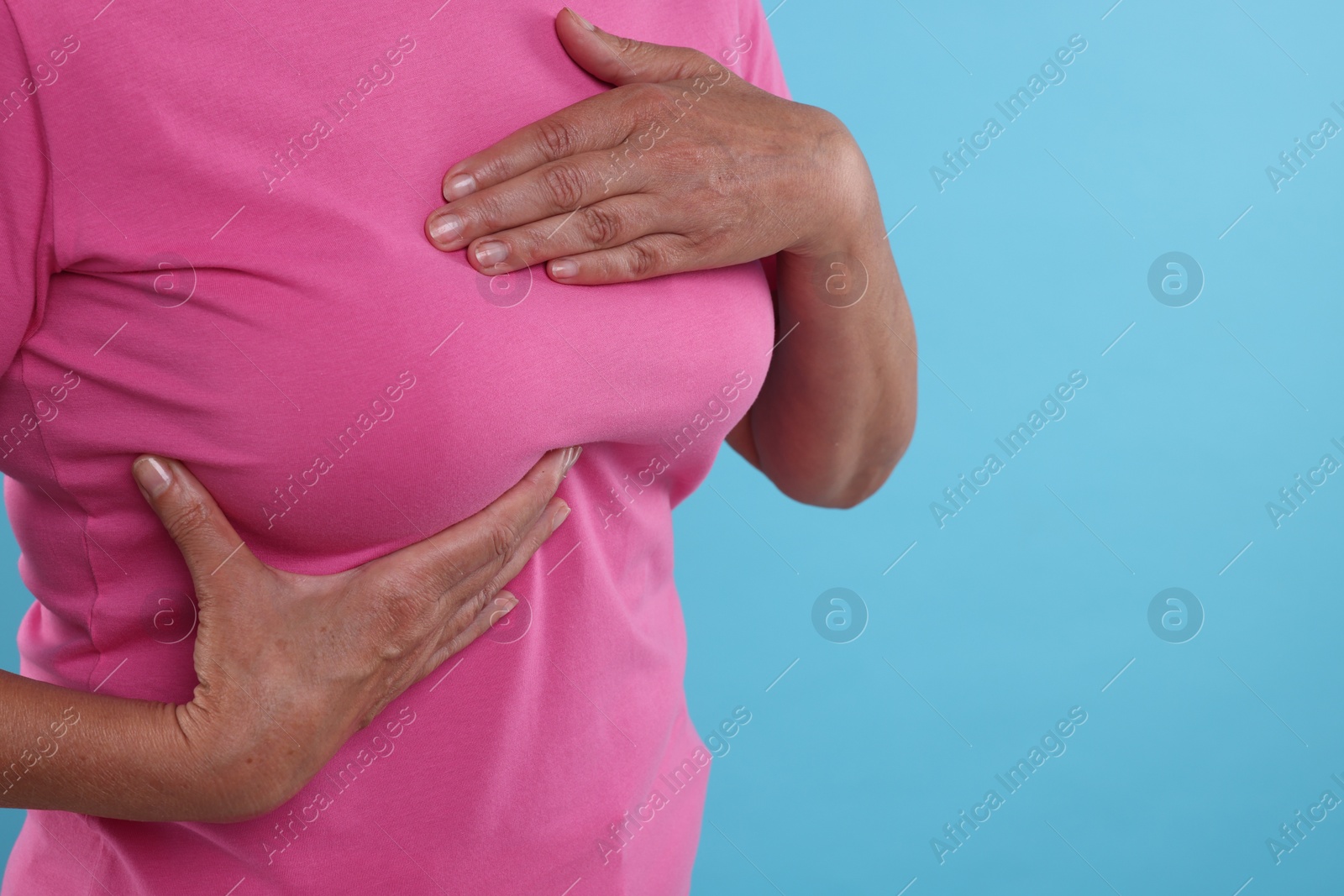 Photo of Woman doing breast self-examination on light blue background, closeup. Space for text