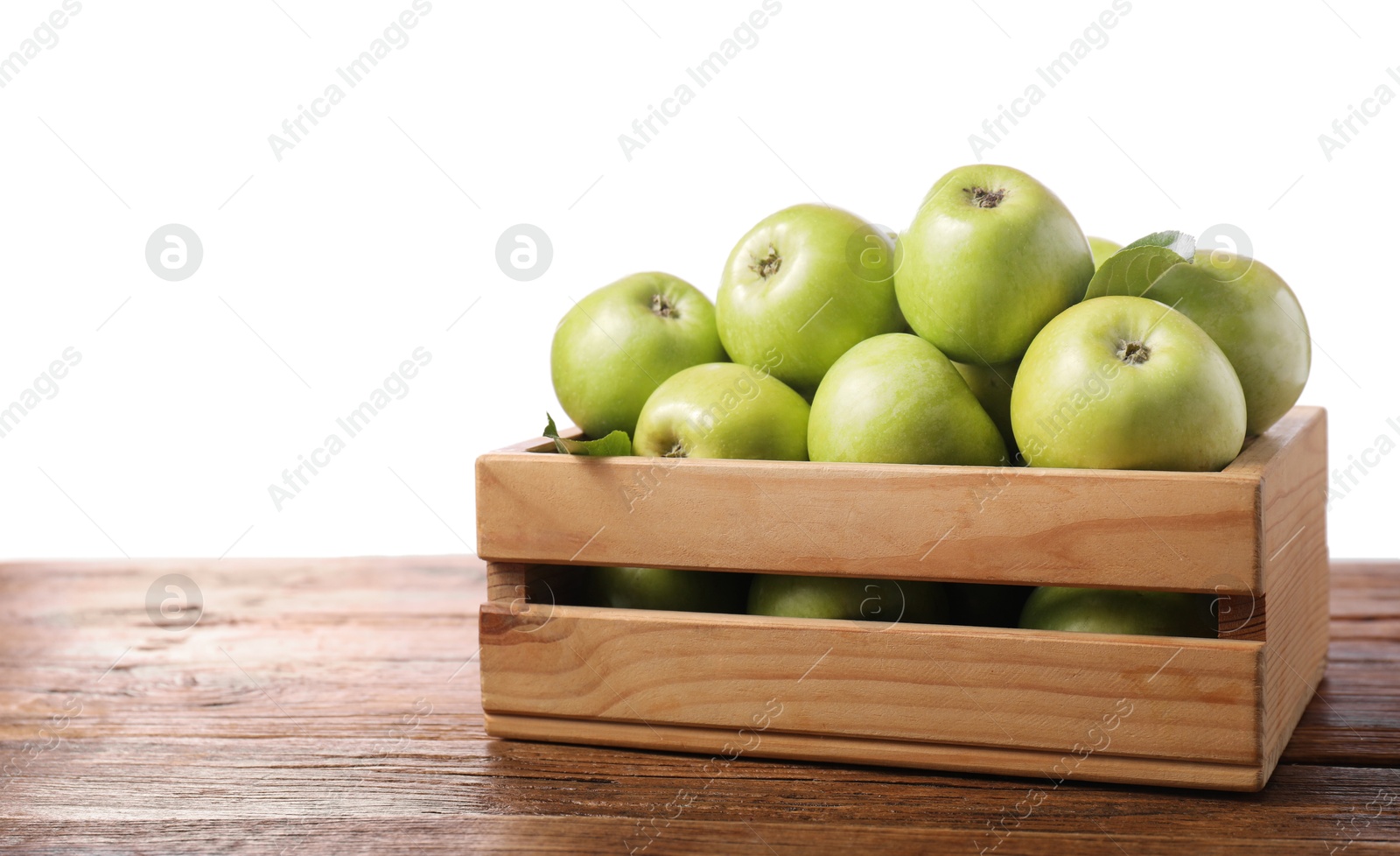 Photo of Ripe green apples in crate on wooden table against white background