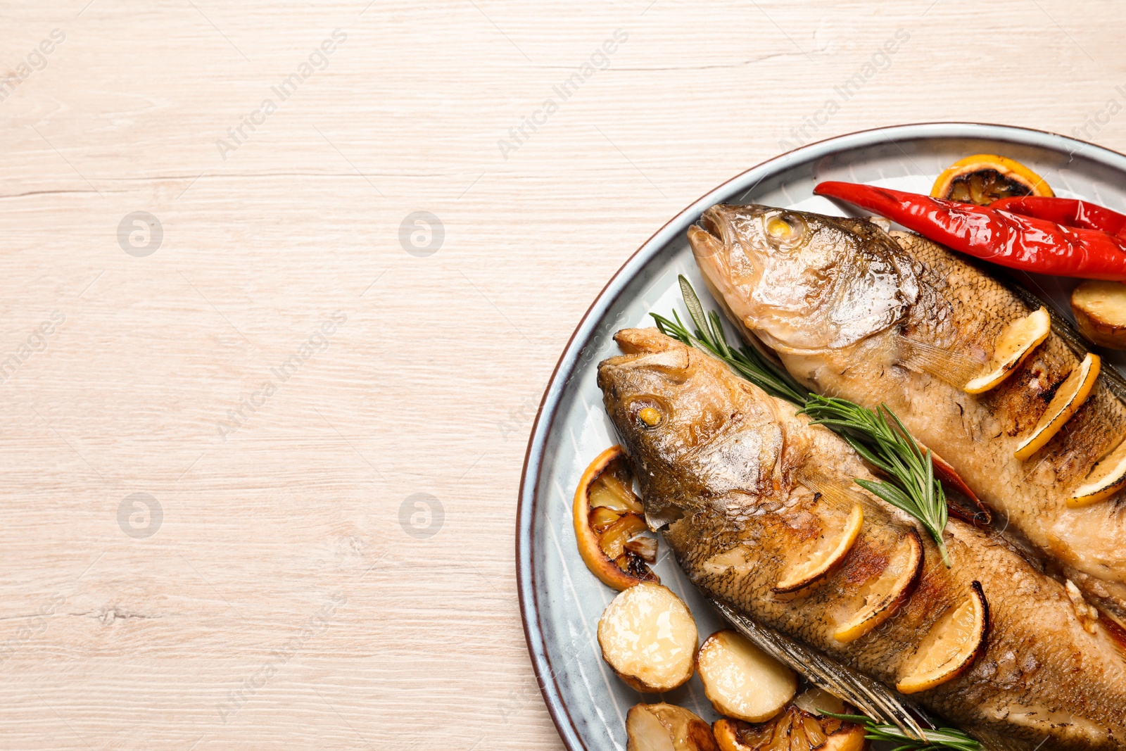 Photo of Tasty homemade roasted perches with garnish on wooden table, top view and space for text. River fish