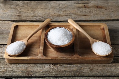 Photo of Organic salt in bowl and spoons on wooden table