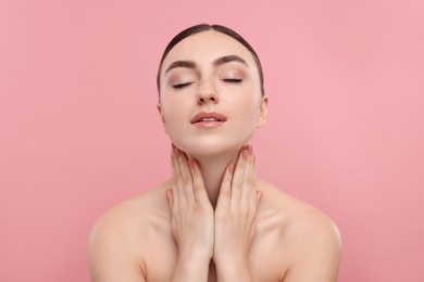 Photo of Beautiful woman touching her neck on pink background