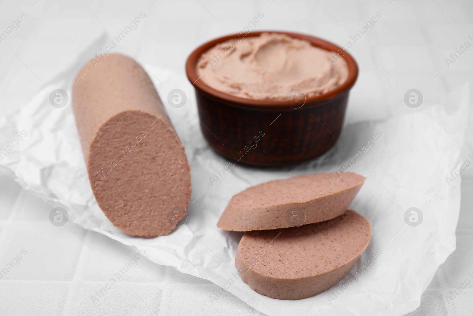 Photo of Delicious liver sausage and paste on white tiled table